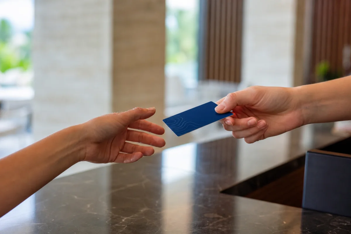 A thin unbranded hotel key card being handed to a guest at a resort reception desk